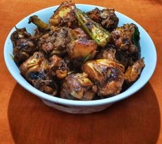 a bowl filled with meat and vegetables on top of a wooden table