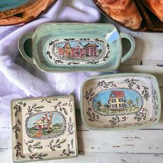 three ceramic dishes with designs on them sitting next to bread and baguette rolls