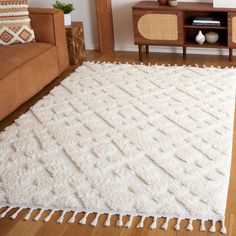 a living room with a brown couch and white rug