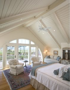 a bedroom with a large bed and two chairs next to each other on a wooden floor