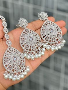 Statement Detailed Earrings with Matching Tikka. White Bead Contrast In Silver Finish Statement Accessory Item to bling up any outfit to wear at any special occasion Reception White Jhumkas With Intricate Design, White Hand Set Bridal Earrings For Party, Hand Set White Bridal Earrings For Party, Silver Cutdana Sets For Wedding, White Jhumkas With Intricate Design For Reception, Silver Bridal Earrings With Stone Work For Reception, Silver Sets With Intricate Design For Reception, White Jhumkas For Wedding, Traditional Silver Bridal Accessories For Wedding