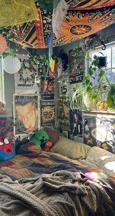 an unmade bed sitting in a bedroom next to a window with lots of hanging plants