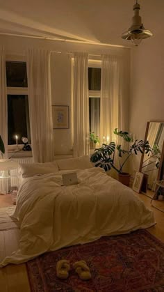 a bed sitting in a bedroom next to a window filled with plants and candles on top of a wooden floor