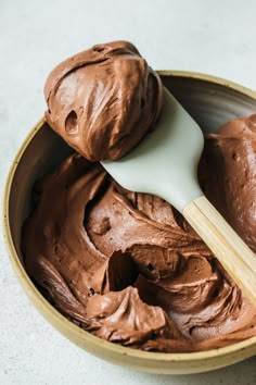 a bowl filled with chocolate frosting and a wooden spoon