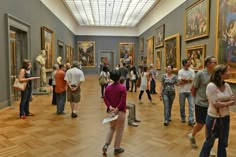 a group of people standing in a museum looking at paintings on the walls and ceiling