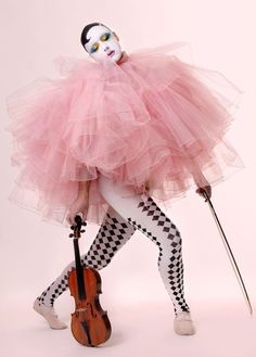 a woman in a pink tutu and mask holding a violin