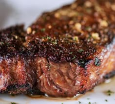 a piece of steak is sitting on a plate with some seasoning sprinkles