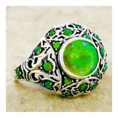 This exquisite piece is a Vintage Estate ring, featuring a green lab-created fire opal as its centerpiece, set within an intricate filigree design. Complementing the central stone are green lab-created opal accent stones, adding to the ring's overall allure. The ring is crafted from 925 solid sterling silver, ensuring both quality and durability. The dimensions of the ring are noteworthy, with the top measuring just over 1/2 inch in length, providing a substantial and elegant presence on the fin Unique Green Sterling Silver Opal Ring, Unique Green Cabochon Opal Ring, Green Opal Ring In Sterling Silver As Gift, Gift Green Opal Ring In Sterling Silver, Green Opal Ring In Sterling Silver For Gift, Green Cabochon Opal Ring, Green Opal Cabochon Ring, Green Opal Ring Gift, Green Opal Ring As A Gift