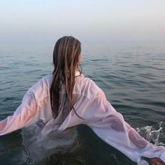 a woman sitting on top of a boat in the ocean with her hair blowing back