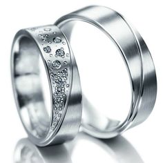 two wedding rings with diamonds on each side, one is white gold and the other is silver