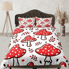 a bed with red mushrooms on it and white polka dot sheets in front of a lamp