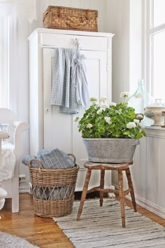 a room with white walls and wooden flooring, baskets on stools next to the window