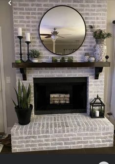 a living room with a fireplace, mirror and potted plants on the mantel