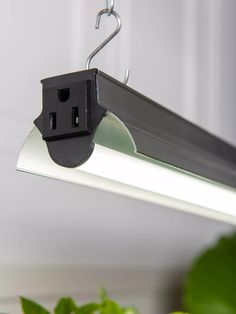 an electrical device is hanging from a metal hook on a light fixture in a room