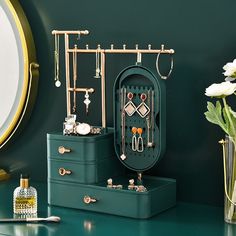 an assortment of jewelry sits on a green table next to a vase with white flowers