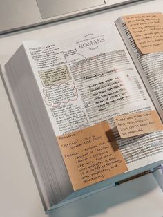 an open book with sticky notes attached to it sitting on top of a computer keyboard