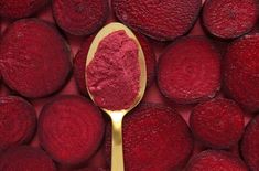 a spoon filled with red powder on top of a pile of beets