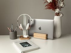 an apple computer sitting on top of a desk next to a book and pen holder