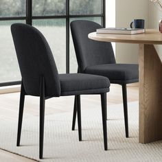 two chairs sitting next to each other on top of a rug in front of a table