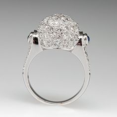 This awesome ring is centered with a domed setting accented with forty-seven (47), bead set, round brilliant cut diamonds. The shoulders of the ring are each accented with one (1), bezel set, round cabochon cut natural sapphire and eight (8), bead set, round brilliant cut diamonds. The ring measures 13.5mm at the top, rises 10.1mm above the finger, tapering to 2.5mm wide and 1.1mm thick at the base of the shank. This ring is currently a size 6.75. Luxury Oval Cluster Ring With Single Cut Diamonds, Dazzling Sapphire Ring With Brilliant Cut Diamond, Oval Sapphire Ring With Pave Setting In Platinum, Classic Multi-stone Diamond White Diamond Ring, Luxury Round Ring With Diamond Accents, Diamond White Cluster Ring In Fine Jewelry Style, Luxury Round Rings With Diamond Accents, Classic Multi-stone Platinum Diamond Ring, Luxury Cluster Ring With Pave Setting For Formal Occasions