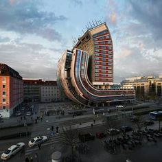 an unusual building in the middle of a parking lot with lots of cars parked around it