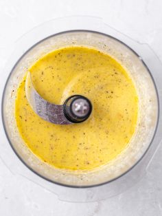 a blender filled with yellow liquid on top of a white counter