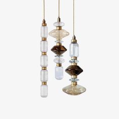 three glass and brass chandeliers hanging from chains on a white background, with one light bulb turned upside down