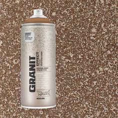 a can of spray paint sitting on top of a brown floor covered in speckles