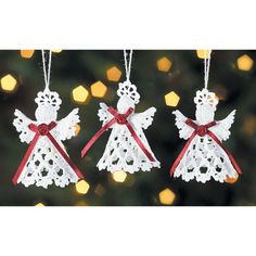 three white angel ornaments hanging from a christmas tree