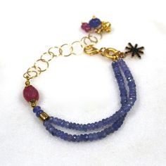 Glittering, vibrantly hued genuine polished natural periwinkle hued tanzanite, one of the rarest and most prized of all gemstones, sparkles on this strand in a beautiful bright striking splash of color! A plump faceted pink sapphire accents the side of the wrist. 14k gold fill chain and colorful drop embellishments add a little chic bling. l Blue Tanzanite Gemstone Bracelets, Blue Amethyst Beaded Bracelets As Gift, Blue Amethyst Beaded Bracelets For Gift, Handmade Blue Amethyst Bracelets, Blue Tanzanite Bracelet Jewelry, Blue Amethyst Bracelets With Natural Stones, Tanzanite Gemstone Bracelet Jewelry, Blue Faceted Amethyst Jewelry, Faceted Blue Amethyst Jewelry