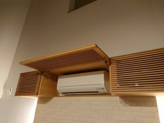 a white air conditioner sitting on top of a wooden shelf