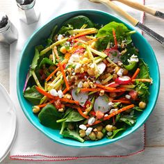 a salad with carrots, lettuce and chickpeas in a blue bowl