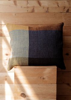 a pillow sitting on top of a wooden bench next to a wall with wood planks