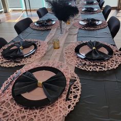 the table is set with black and pink place settings