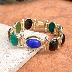 Estate/ vintage 14KT yellow gold oval, genuine, green onyx, blue onyx, black onyx, jasper, agate, scarab bracelet. Bullet spacer details between the gemstone links. Amazing, carved, scarab design on some of the pieces, others plain. Length: 8” Weight: 34.36 grams Band width: 12.5mm at widest Hallmarked and stamped 14K Push In clasp Good estate condition Some repaired work has been done to this piece Scarab Bracelet, Saint Jewelry, Blue Onyx, Green Onyx, Black Onyx, Link Bracelets, Onyx, Agate, Bangles