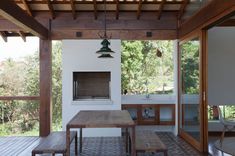 an outdoor kitchen and dining area with wood flooring, white walls and wooden ceiling