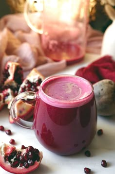 a cup of hot chocolate with pomegranates on the table next to it