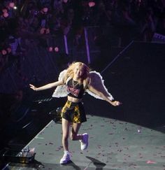 a woman with angel wings is dancing on the stage in front of an audience at a concert