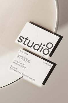 two business cards sitting on top of each other in front of a circular object that reads studio