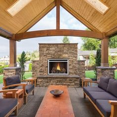 an outdoor living area with couches, tables and a fireplace in the middle of it