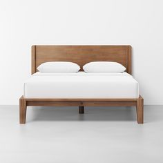 a bed with two pillows on top of it and a wooden headboard in the middle