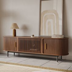 a wooden sideboard sitting next to a lamp on top of a rug in a living room