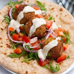 a white plate topped with falafel covered in sauce and veggies