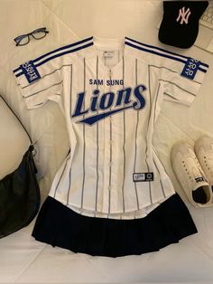 a baseball uniform is laying on the bed next to some shoes and a handbag