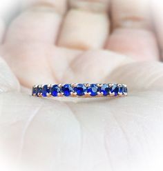 Full Eternity Band Ring with Natural Royal Blue Sapphires. MaterialSolid Gold (14K & 18K) or PLATINUM 950 FinishingHigh Polished/ Shiny PlatingOnly if WHITE GOLD - Rhodium/ Platinum Family FitComfort/ Rounded Width2.3 mm Height2 mm Setting TypePave StoneNatural Blue Sapphire QualityAAA Shape & CutRound, Diamond Cut Stone Size2 mm Quantity of Stones: apx 32 Click below to add laser engraving. https://www.etsy.com/listing/631070916/laser-engraving?ga_search_query=laser%2Bengraving&ref= Blue Round Eternity Band For Anniversary, Blue Gemstone Eternity Band In Fine Jewelry Style, Blue Round Eternity Band With Prong Setting, Blue Eternity Band For Promise, Blue Half Eternity Round Ring, Blue Sapphire Promise Ring With Half Eternity, Blue Sapphire Half Eternity Ring For Promise, Blue Sapphire Half Eternity Ring As Gift, Blue Sapphire Anniversary Ring With Round Band