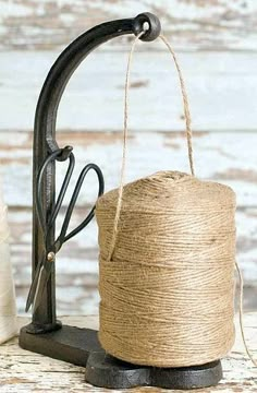 a spool of twine hanging from a faucet on a wooden table