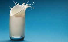 a glass filled with milk on top of a blue table