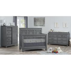 a baby crib and dresser in a room with hardwood floors, gray walls and furniture