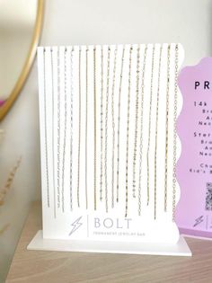 a white card with gold chains on it next to a pink box and some other items