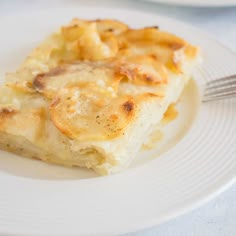 a piece of food on a plate with a fork next to it and another dish in the background